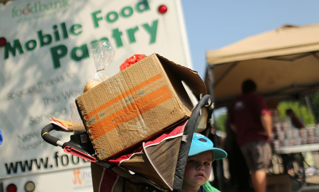 A child waits with a box of food at a mobile food bank in Oswego, N.Y., in June. New census data show that 46.2 million people in the U.S. lived below the poverty line last year. A child waits with a box of food at a mobile food bank in Oswego, N.Y., in June. New census data show that 46.2 million people in the U.S. lived below the poverty line last year.