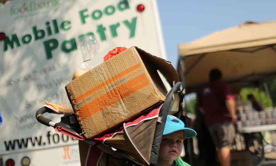 A child waits with a box of food at a mobile food bank in Oswego, N.Y., in June. New census data show that 46.2 million people in the U.S. lived below the poverty line last year.