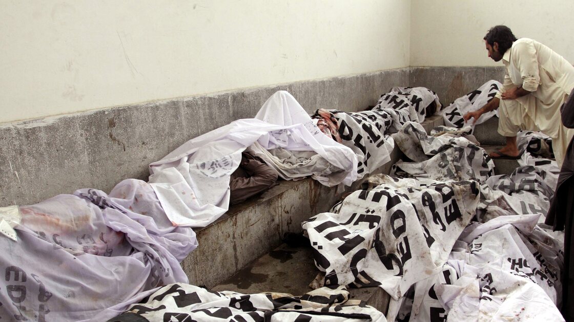 A man tries to identify body of his relative at a mortuary following a huge fire at a garments factory in Karachi, Pakistan.