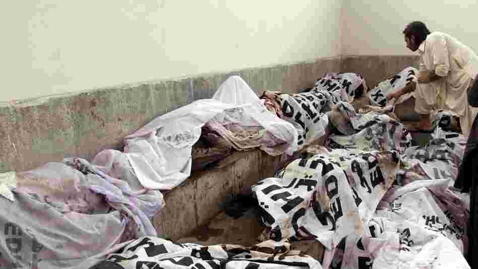 A man tries to identify body of his relative at a mortuary following a huge fire at a garments factory in Karachi, Pakistan.