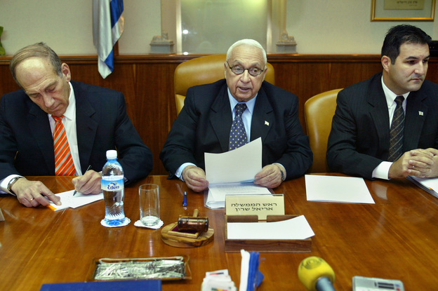 Sharon, flanked by Deputy Prime Minister Ehud Olmert (left) and Cabinet Secretary Yisrael Maimon, reads a statement during the weekly Cabinet meeting at Sharon's office, on June 13, 2004, in Jerusalem. (Image credit: Getty Images)