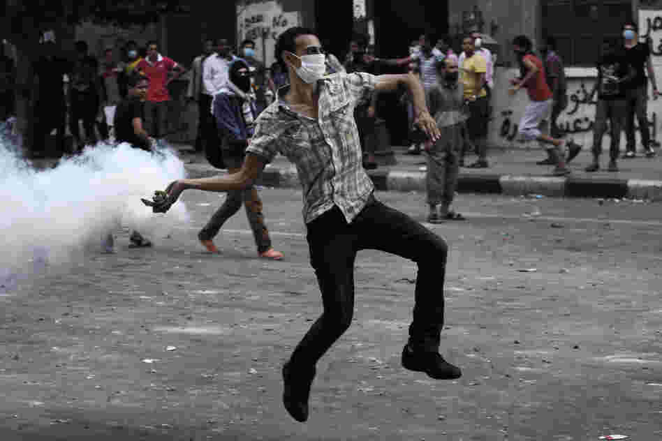 A protester throws a tear-gas canister toward riot police outside the U.S. Embassy in Cairo on Thursday. Dozens were injured in clashes, according to state TV.