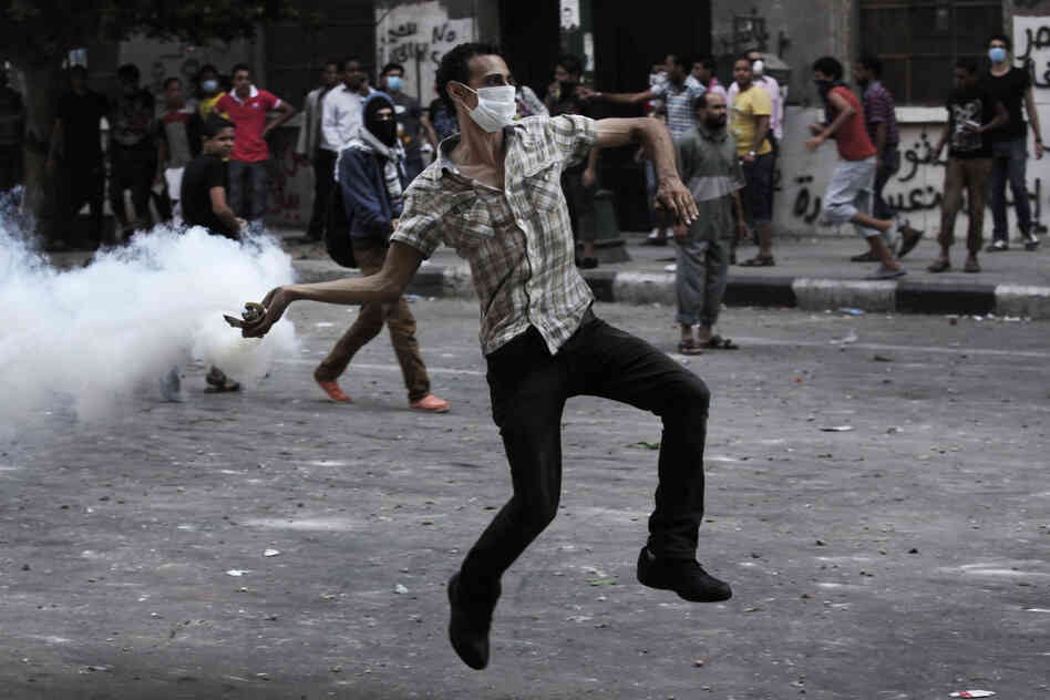 A protester throws a tear-gas canister toward riot police outside the U.S. Embassy in Cairo on Thursday. Dozens were injured in clashes, according to state TV.
