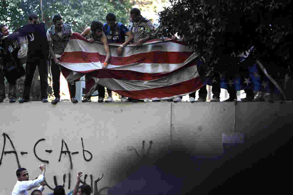 Protesters carry an American flag pulled down from the U.S. embassy in Cairo, Egypt on Tuesday.