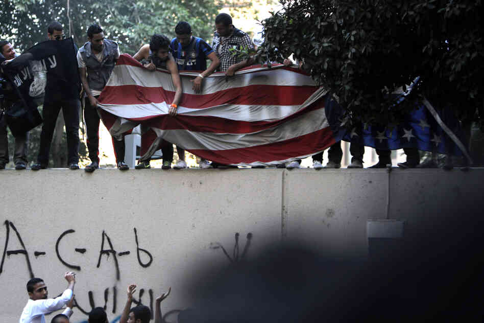 Protesters carry an American flag pulled down from the U.S. embassy in Cairo, Egypt on Tuesday.