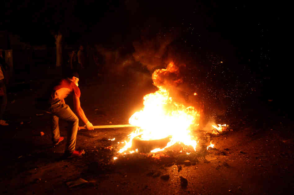 A protester sets a tire on fire during clashes with police in front of the U.S. Embassy in Cairo.