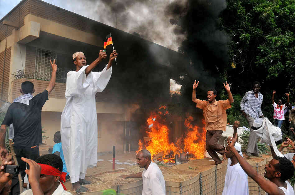 A Sudanese demonstrator burns a German flag as others shout slogans after torching the German embassy in Khartoum during a protest against a low-budget film mocking Islam on Friday. Around 5,000 protesters in the Sudanese capital angry over the amateur anti-Islam film stormed the embassies of Britain and Germany, which was torched and badly damaged.