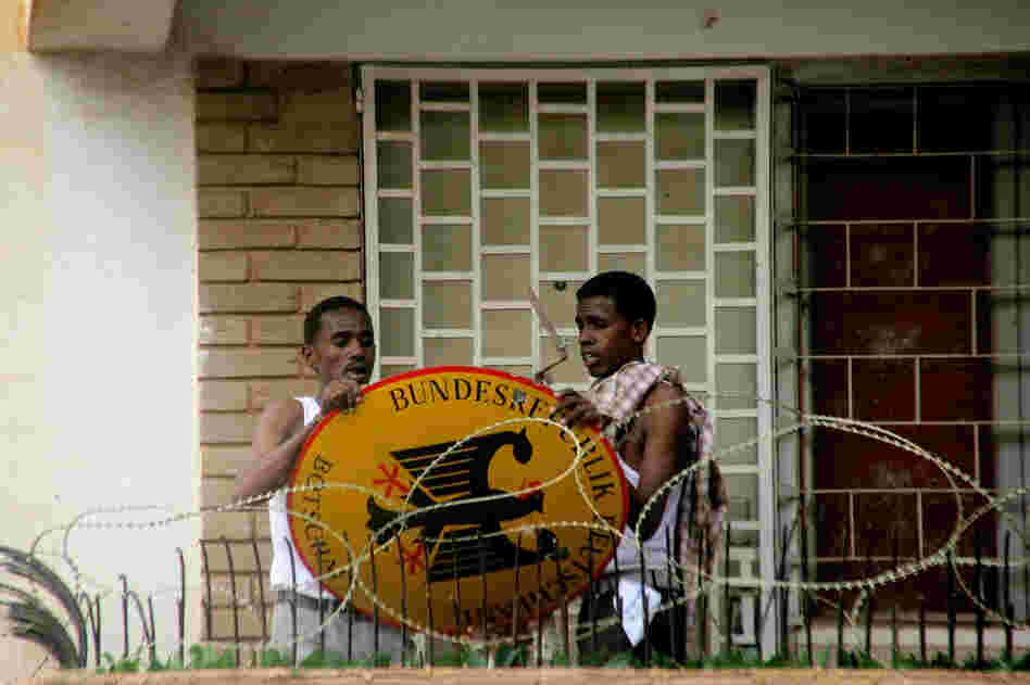 Sudanese demonstrators remove the German embassy sign after storming its premises in Khartoum. 