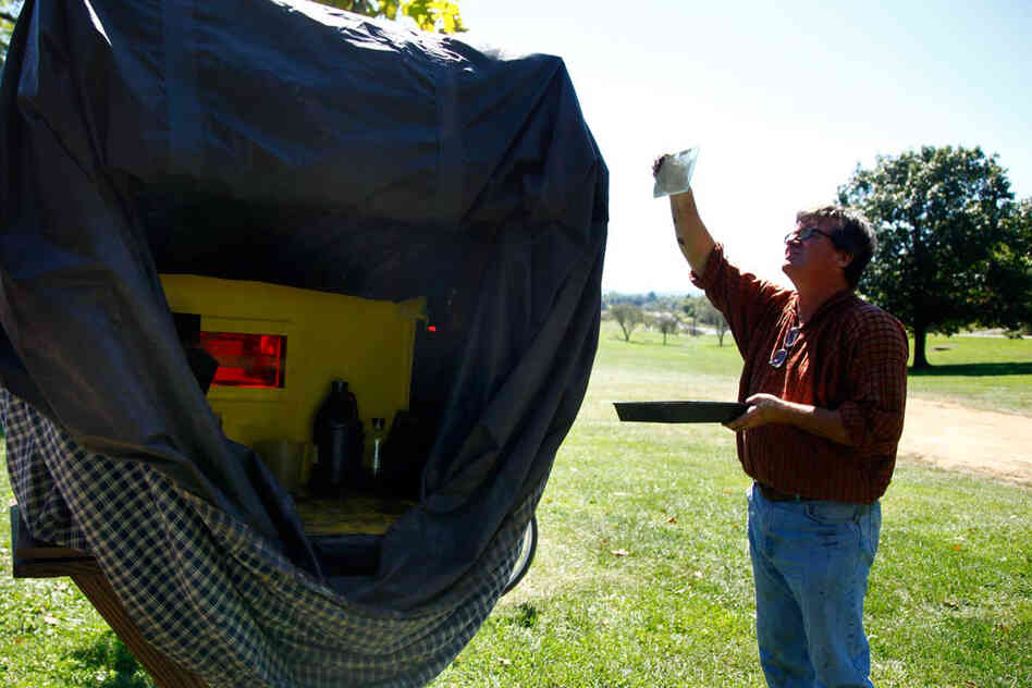 Todd Harrington holds a developed wet plate up to the light to check its exposure.