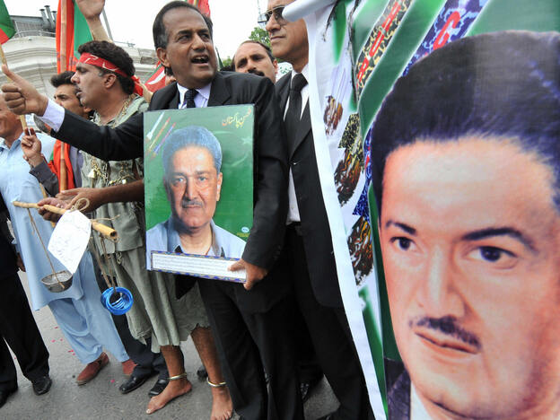 Pakistani lawyers carry posters of Khan at a rally in support of him in Lahore in 2008.