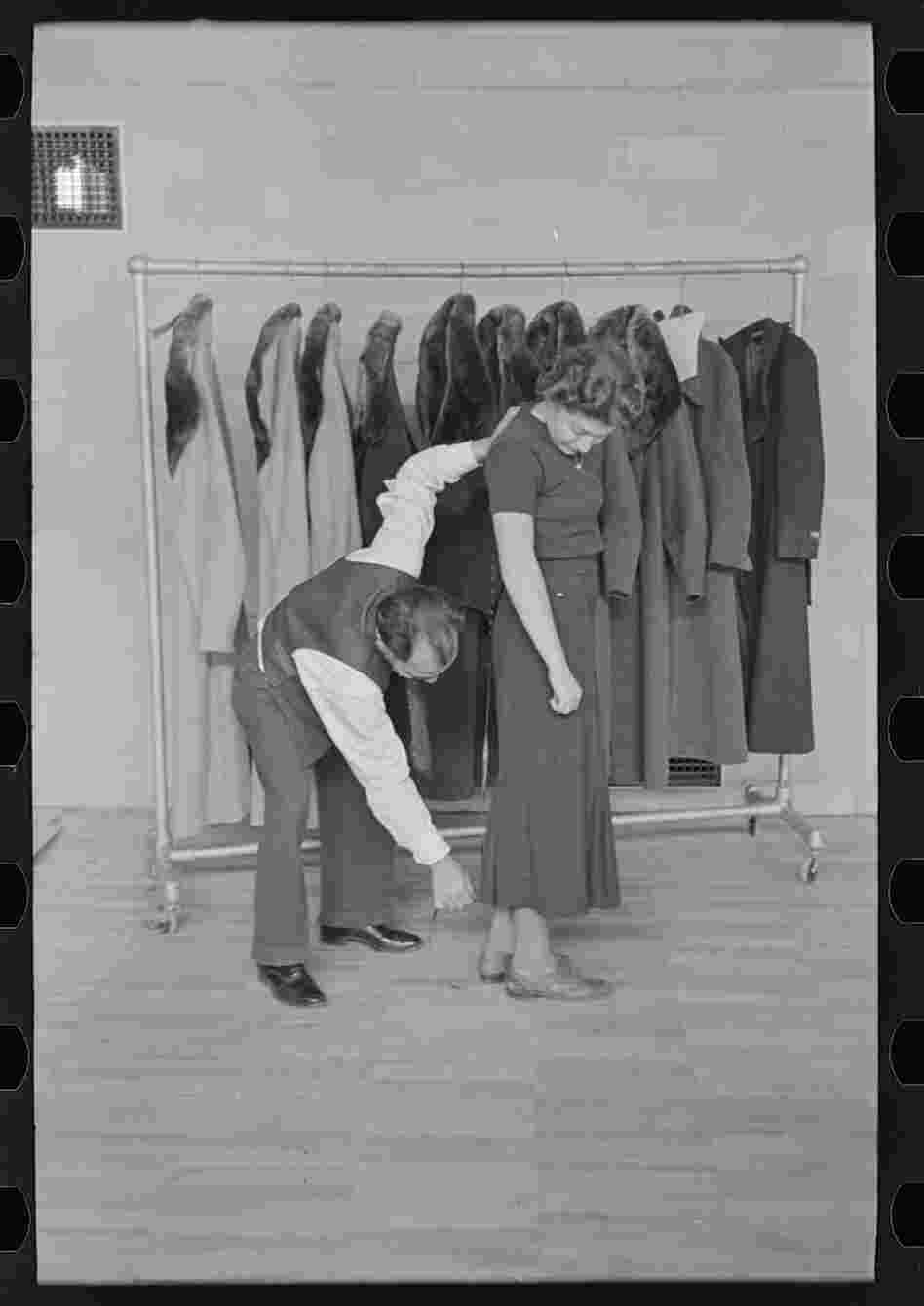 A tailor measures a woman for a coat, which was produced by the town's garment factory.