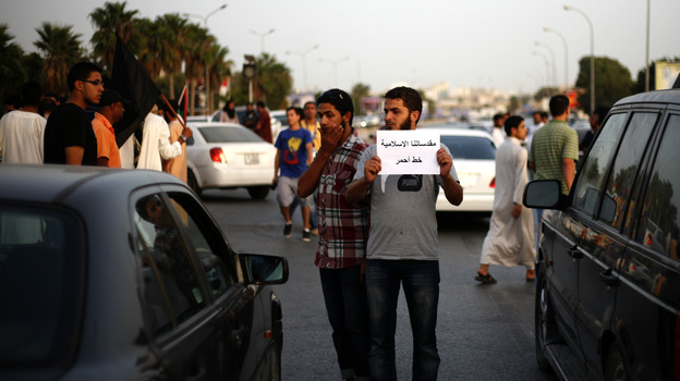 A Libyan follower of Ansar al-Sharia Brigades carries a placard reads in Arabic "our Islamic holies are red line," during a protest in front of the Tibesti Hotel, in Benghazi, Libya, on Sept. 14, as part of widespread anger across the Muslim world about a film ridiculing Islam's Prophet Muhammad.