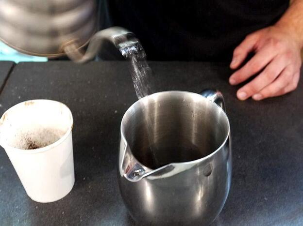 Andrew Shields, a barista at Chinatown Coffee, makes a custom cup of civet coffee, following the instructions to use a French press.