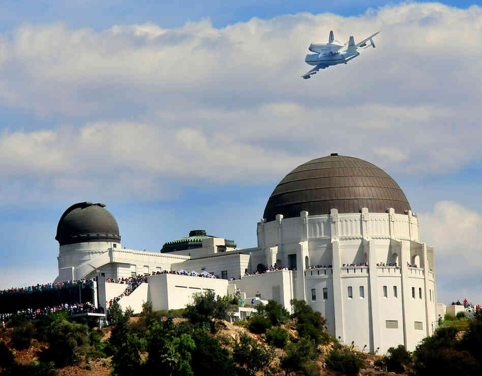 The space shuttle Endeavour flies atop NASA's Shuttle Carrier Aircraft or SCA over the Griffith Park Obervatory in Los Angeles.