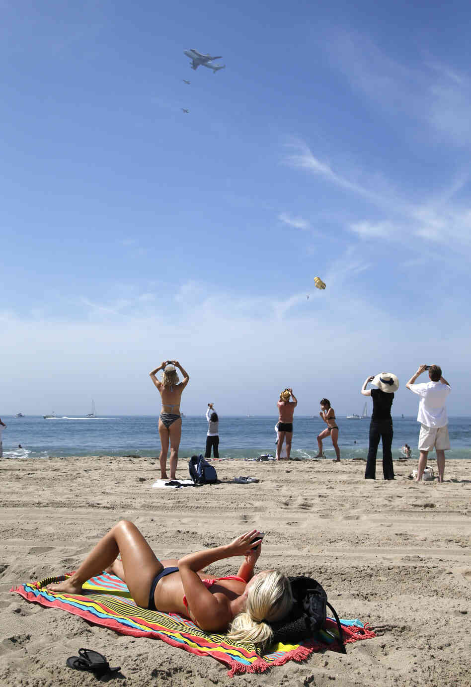 Spectators take pictures with varied levels of excitement, as the Space Shuttle Endeavour, mounted on NASA's Shuttle Carrier Aircraft, flies near Santa Monica.