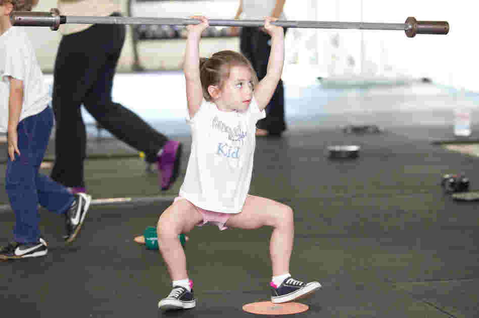 Rose MacDermott, 6, lifts a barbell above her head as part of her CrossFit exercise.