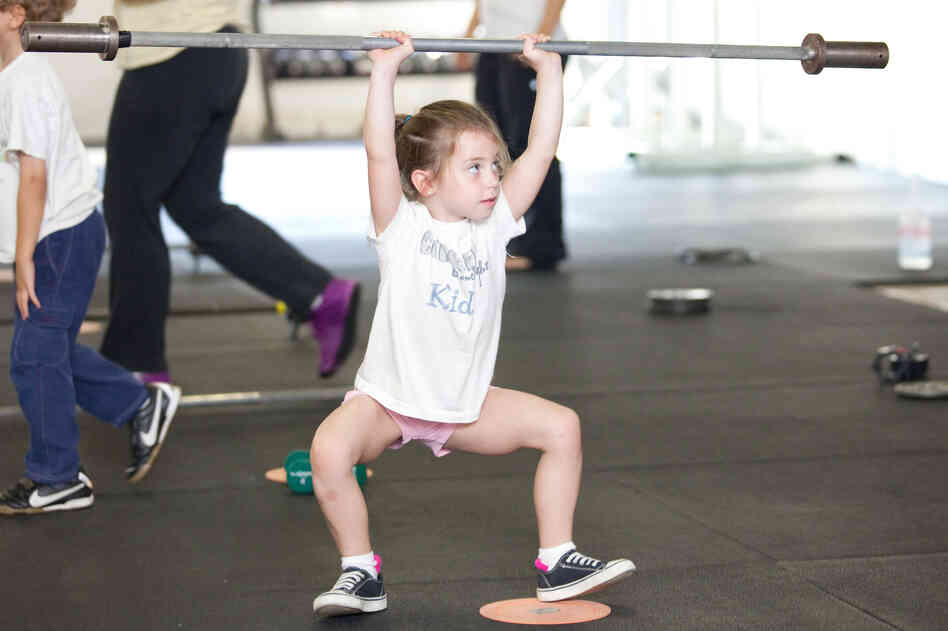 Rose MacDermott, 6, lifts a barbell above her head as part of her CrossFit exercise.