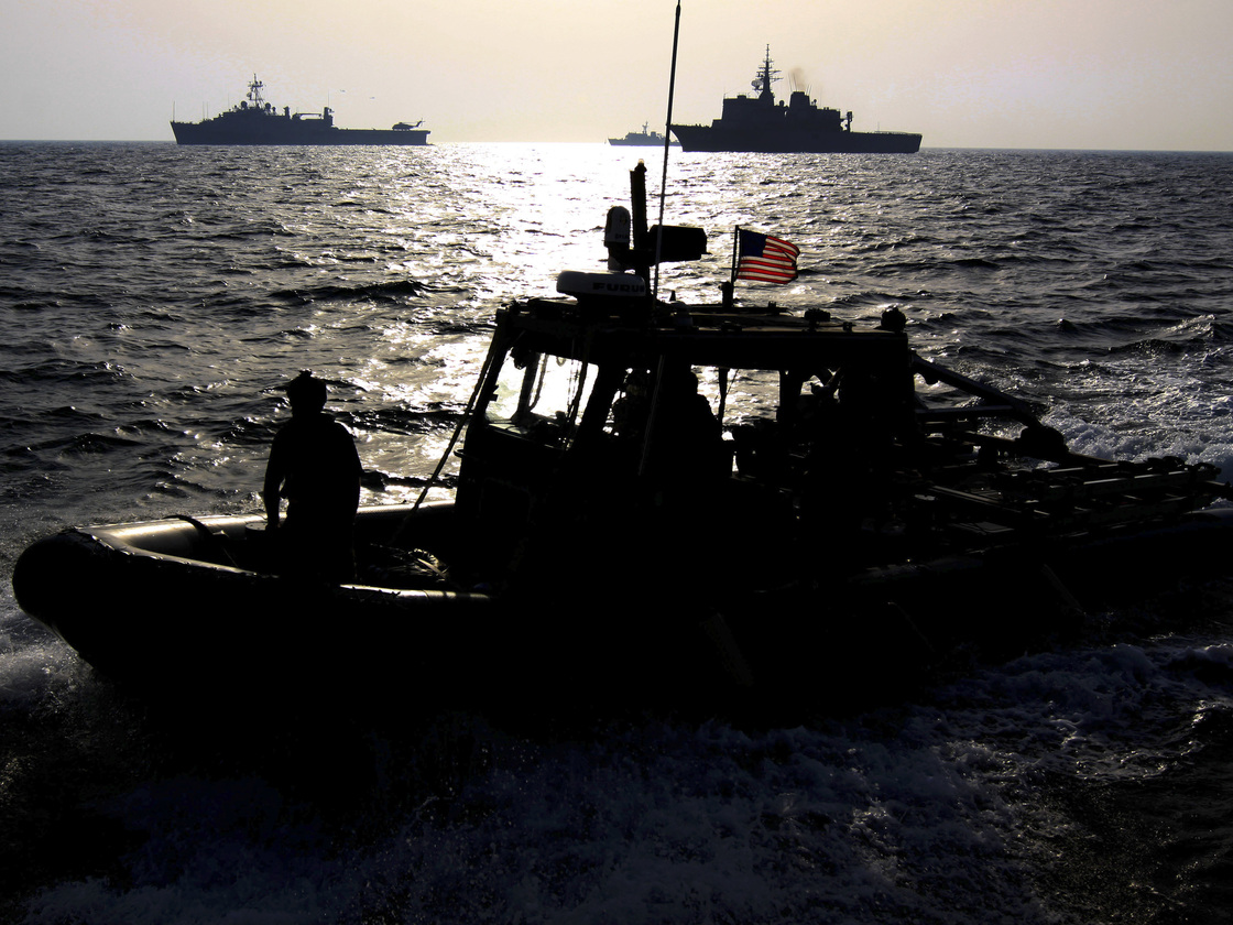 A U.S. Navy speedboat passes in front of multinational military ships in the Persian Gulf on Sept. 21 as part of the military exercise. If attacked, Iran says it will close the Strait of Hormuz, which is a crucial shipping route.