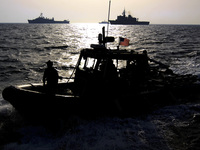 A U.S. Navy speedboat passes in front of multinational military ships in the Persian Gulf on Sept. 21 as part of the military exercise. If attacked, Iran says it will close the Strait of Hormuz, which is a crucial shipping route.