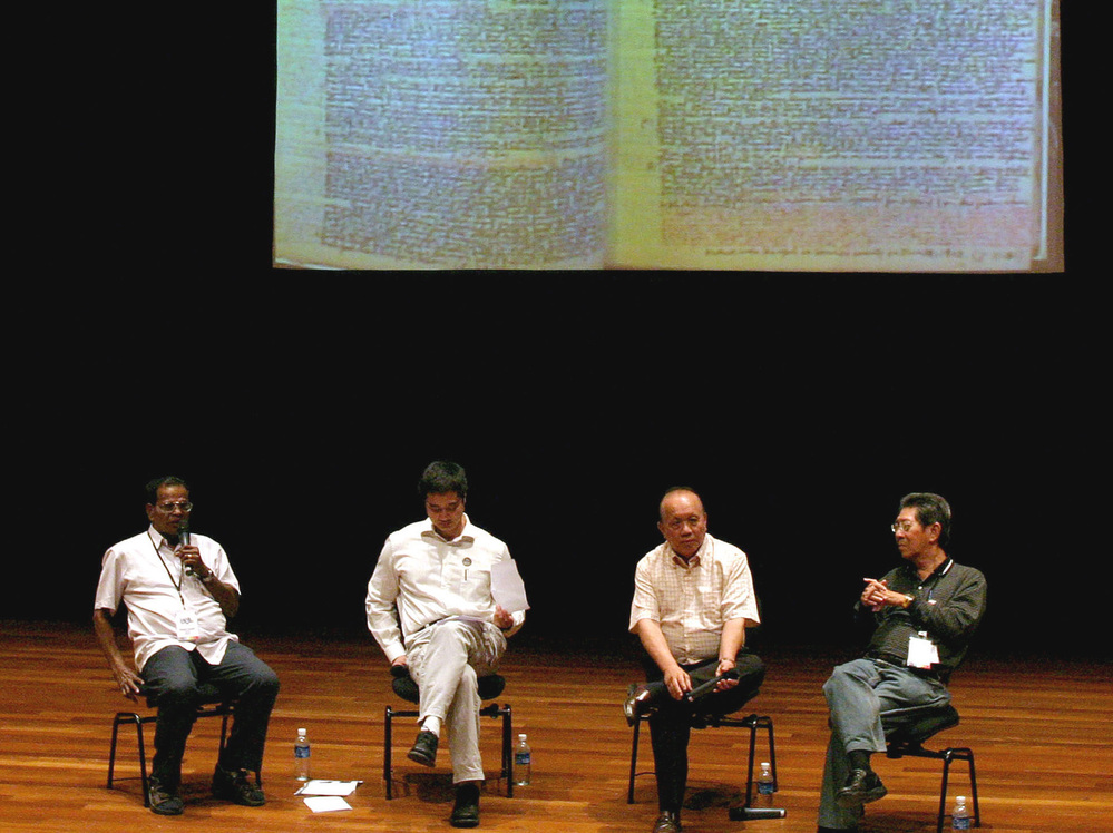 Former political detainees, Michael Fernandez (left), 72, and Tan Jing Quee (second from right), 66, participate in a forum in Singapore. A notebook used by Fernandez to scribble notes while he was jailed is projected behind them at the event held in 2006. Fernandez and Tan are among the hundreds of Singaporeans detained by the government without trial for, they say, political reasons.