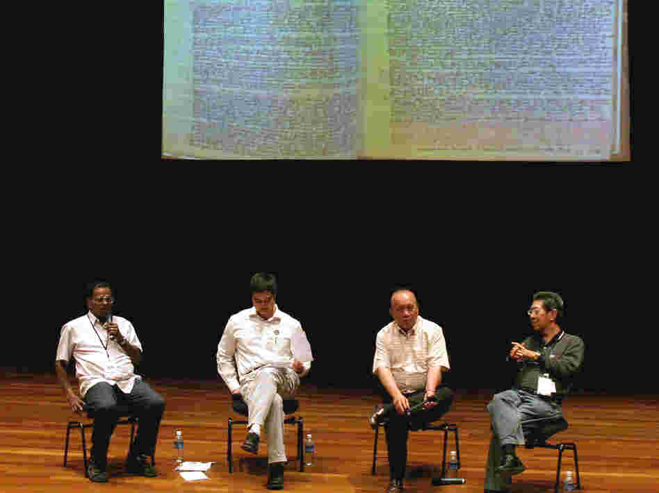 Former political detainees, Michael Fernandez (left), 72, and Tan Jing Quee (second from right), 66, participate in a forum in Singapore. A notebook used by Fernandez to scribble notes while he was jailed is projected behind them at the event held in 2006. Fernandez and Tan are among the hundreds of Singaporeans detained by the government without trial for, they say, political reasons.
