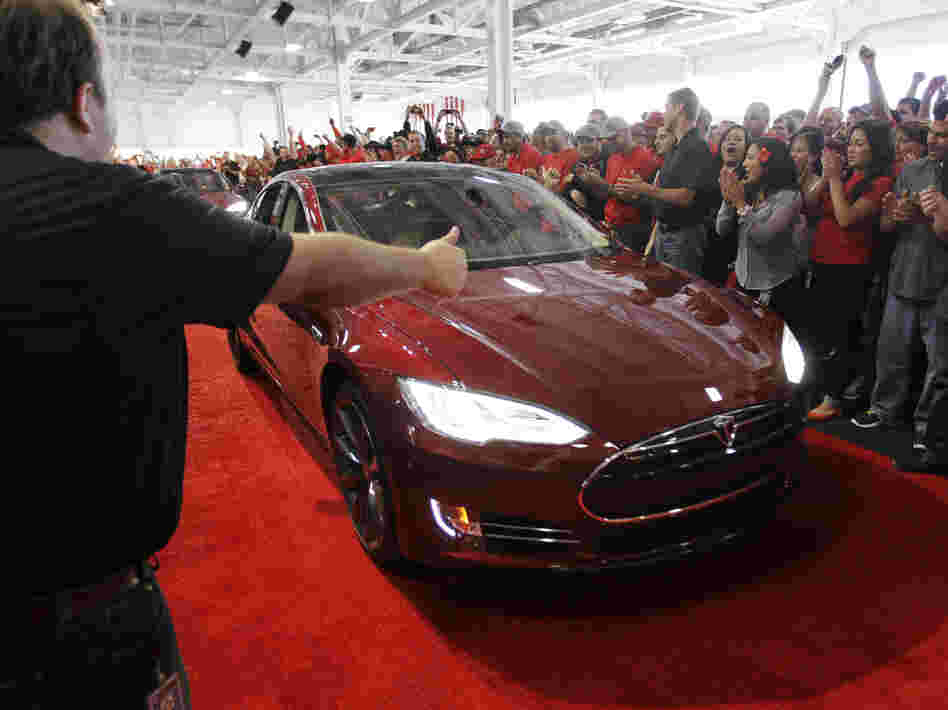 Tesla workers cheer on one of the first Tesla Model S cars sold, during a rally at the Tesla factory in Fremont, Calif., in June. The company is now unveiling a new network of refueling stations for the vehicles.