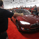 Tesla workers cheer on one of the first Tesla Model S cars sold, during a rally at the Tesla factory in Fremont, Calif., in June. The company is now unveiling a new network of refueling stations for the vehicles.