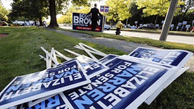 Bill Connell of Weymouth, Mass., who supports Republican Sen. Scott Brown, stands near signs supporting Brown's Democratic challenger, Elizabeth Warren, before the candidates' first debate Thursday in Boston.