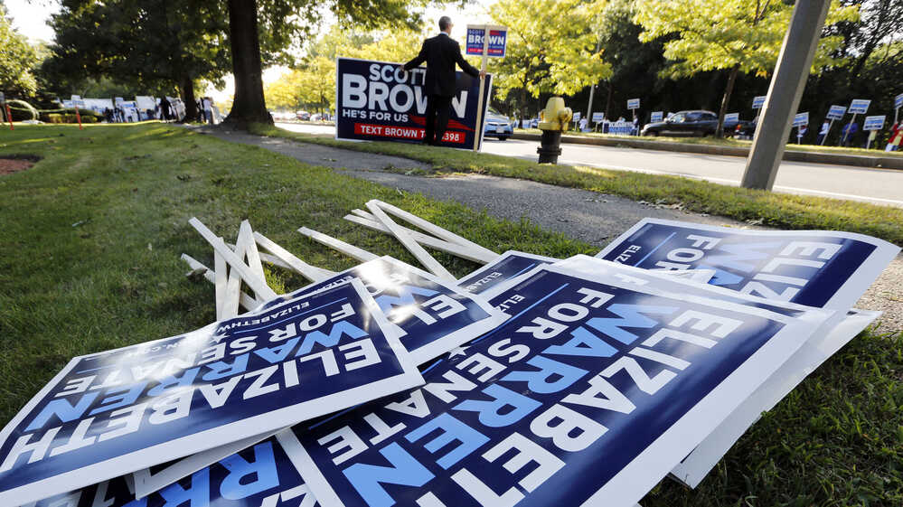 Bill Connell of Weymouth, Mass., who supports Republican Sen. Scott Brown, stands near signs supporting Brown's Democratic challenger, Elizabeth Warren, before the candidates' first debate Thursday in Boston.