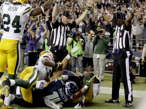 Confusion: One official (to the  left) signals touchdown for Seattle. The other signals that a touchback — possession — for Green Bay.