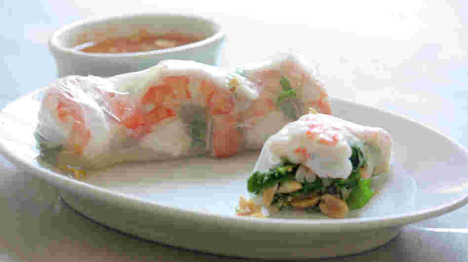 A Classic Summer Roll with shrimp on a plate, with a bowl of dipping sauce in the background
