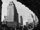 Wall Street skyscrapers are seen from beneath the Third Avenue elevated railway in New York City, circa 1949.