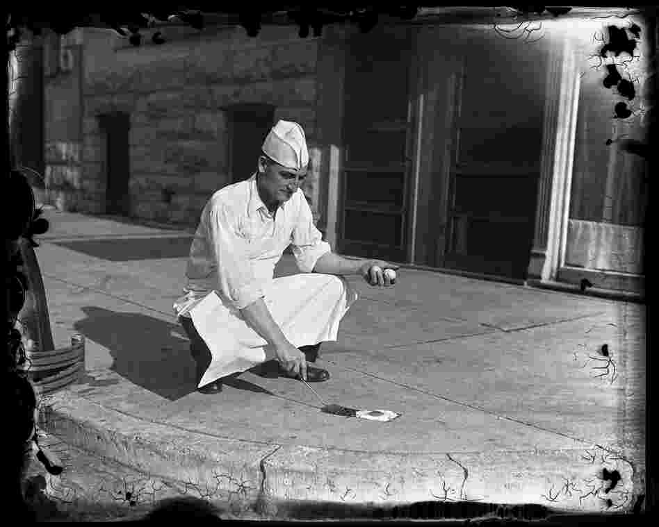 T.M. Travis, owner of Travis Cafeteria at 624 E. Capitol Ave., tries to prove, or disprove, the belief that it is sometimes hot enough to fry an egg on the sidewalk in July 1930. Despite it being 115 degrees on the concrete, the experiment did not work.