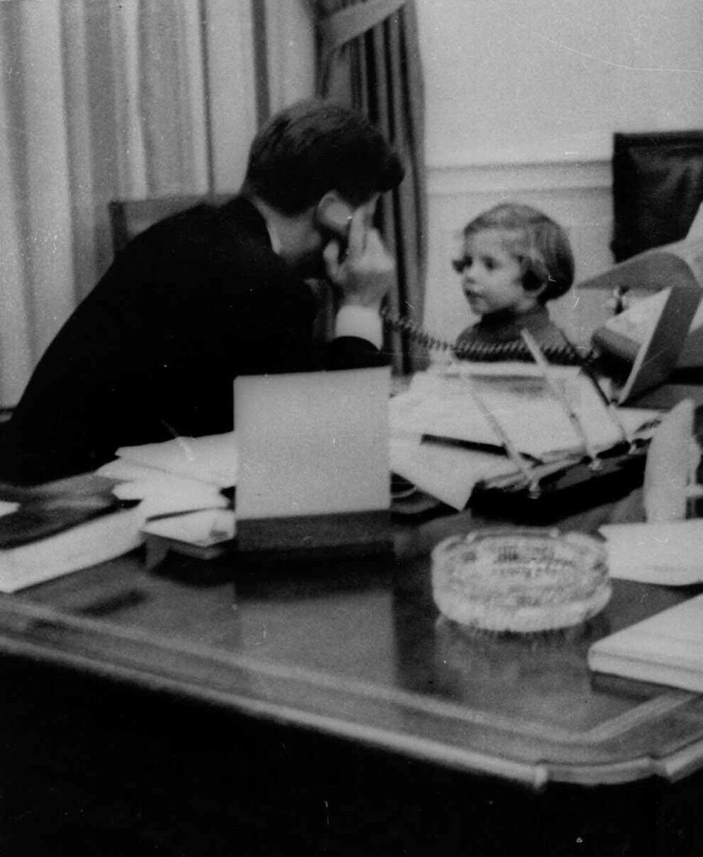 In this photo from March 1961, Kennedy talks on the phone with his wife, Jacqueline Kennedy, with their daughter, 3-year-old Caroline, at his side.