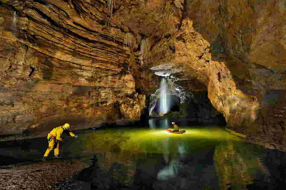Cavers cross Lake Cadoux in a small dingy inside the Gouffre Berger cave. A 4-meter-deep (approximately 13 feet) pool of water blocks the way forward through the Starless River.