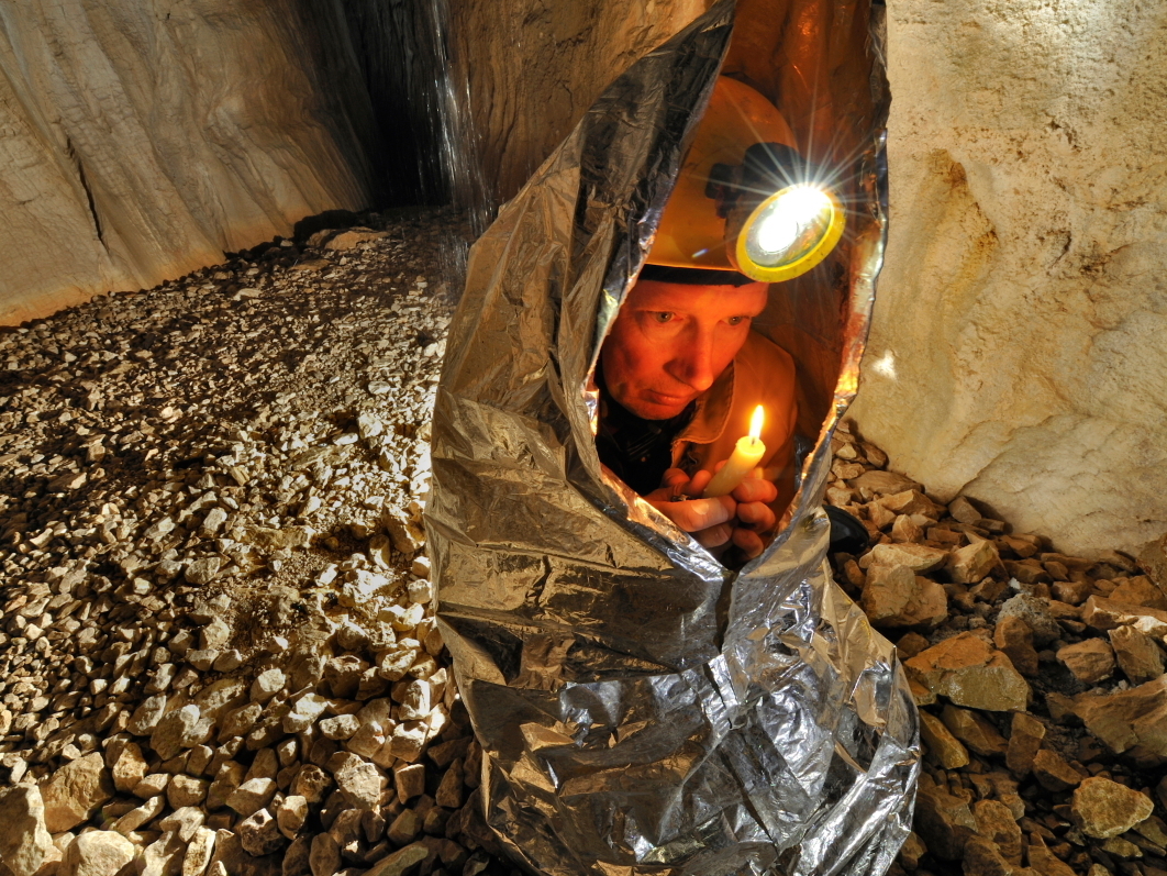 Tim Nixon tries to warm up using the heat from a candle in the Gouffre Berger cave in France.