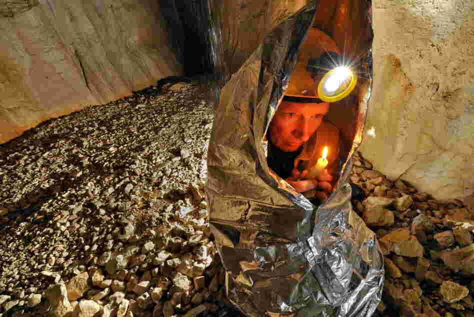 Tim Nixon tries to warm up using the heat from a candle. The temperature in the cave constantly hovers around 4 degrees Celsius (39.2 F). 