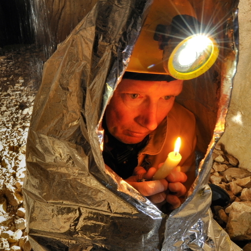 Tim Nixon tries to warm up using the heat from a candle in the Gouffre Berger cave in France.