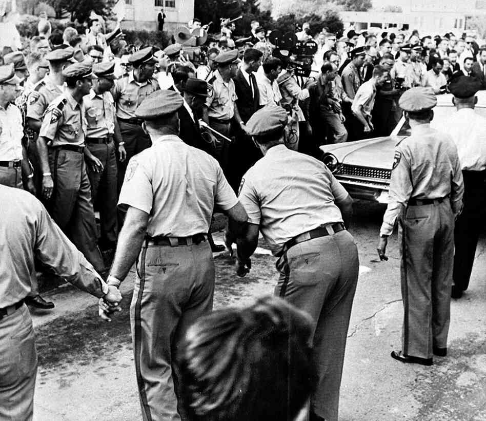 Policemen keep a cheering mob back as Meredith drives away after being refused admittance to the all-white university in Oxford, Miss. It took several attempts for him to enroll, as he was physically blocked on campus by Gov. Ross Barnett.