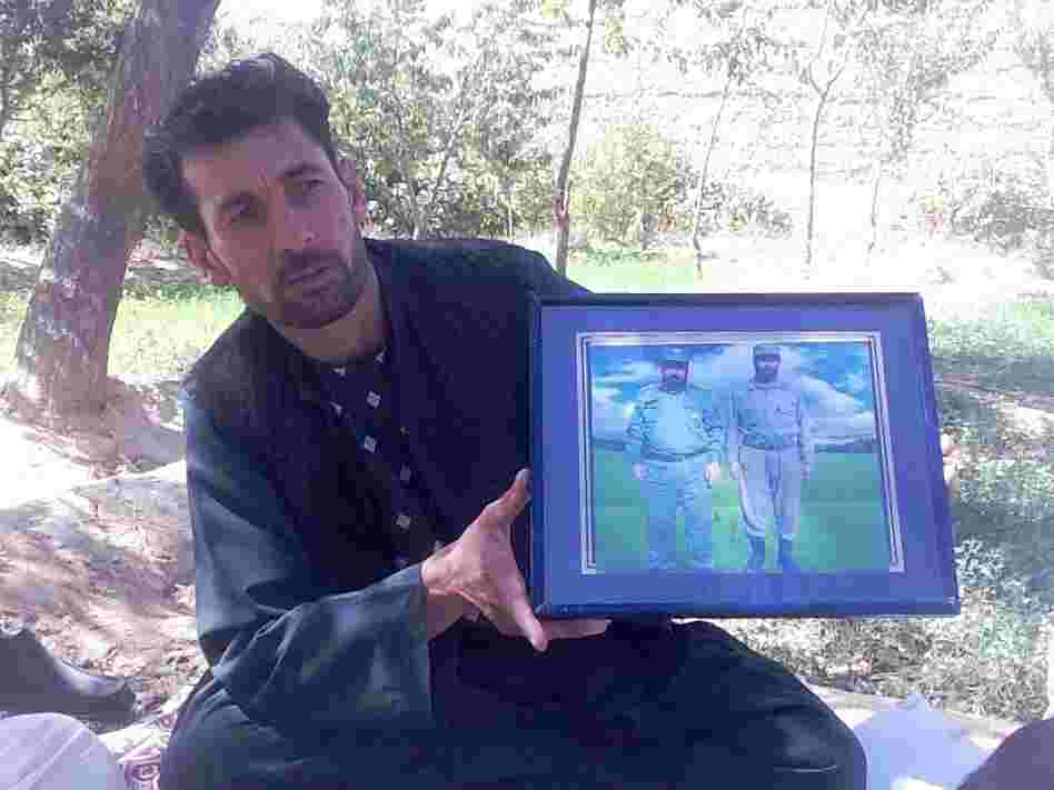 Mohammed Naeem, a driver, holds up a framed photo of two relatives he says were killed by militant leader Abdullah near the western city of Herat.