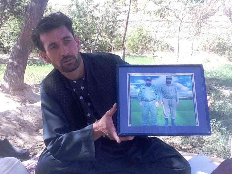 Mohammed Naeem, a driver, holds up a framed photo of two relatives he says were killed by militant leader Abdullah near the western city of Herat.