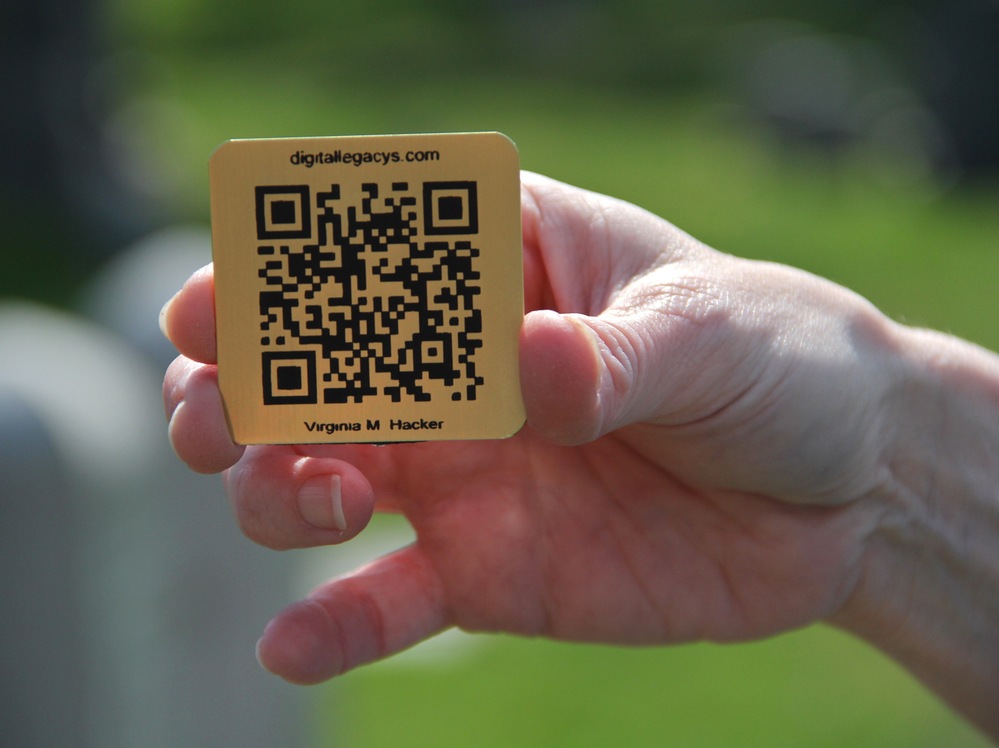Lorie Miller holds the brass QR code for her grandmother's gravestone. Smartphone users who scan it will be directed to an online tribute.