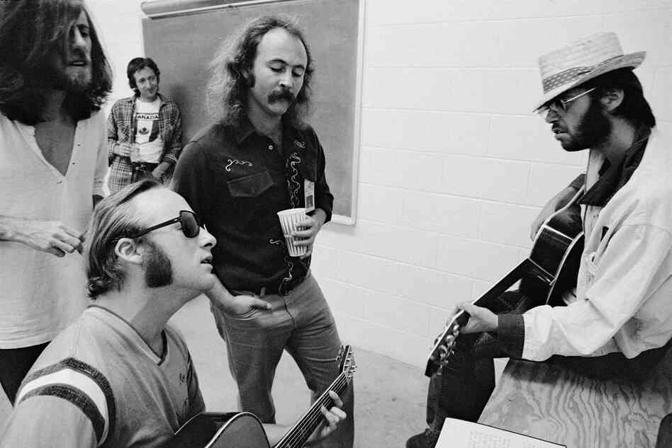 Left to right: Graham Nash, Stephen Stills, David Crosby and Neil Young, with Elliot Roberts in the background, backstage before a CSNY show in Denver, 1974.