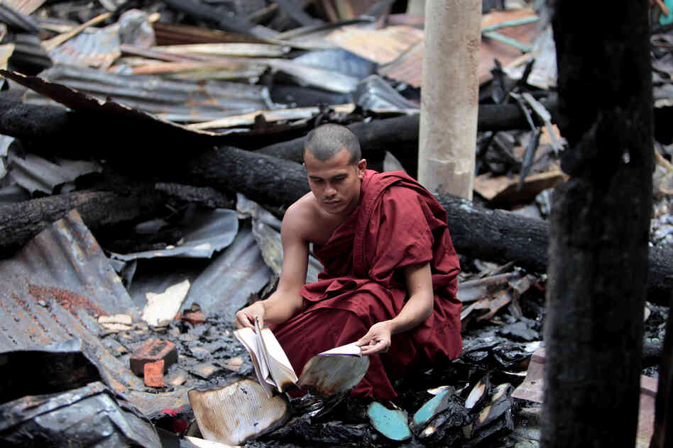 A Bangladeshi Buddhist monk checks the remains of burned religious books at a Buddhist temple which was torched in an overnight weekend attack in Ramu in the coastal district of Cox's Bazar, Bangladesh on Monday.