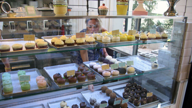 Nicole Kotovos arranges cupcakes in the case at her store in Athens.