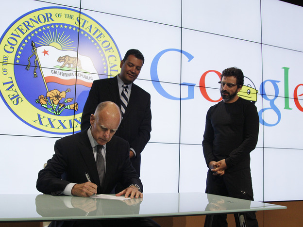 California Gov. Jerry Brown signs a bill for driverless cars as state Sen. Alex Padilla (left) and Google co-founder Sergey Brin look on. The legislation opens the way for driverless cars in the state.