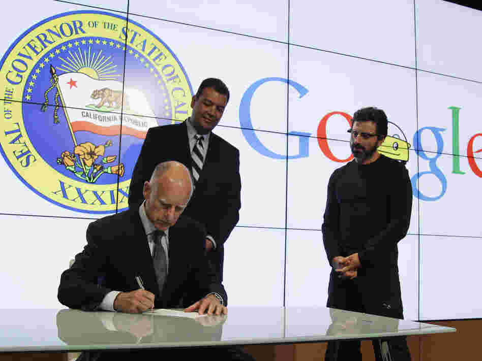 California Gov. Jerry Brown signs a bill for driverless cars as state Sen. Alex Padilla (left) and Google co-founder Sergey Brin look on. The legislation opens the way for driverless cars in the state.