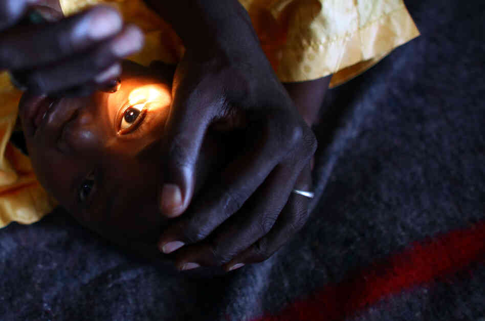 A health worker looks for signs of vision in the eyes of Yusuf Labbo. Severe lead poisoning has left the 5-year-old boy blind. He weighs just 22 pounds, can't speak or walk and spends most of his days clutched in his mother's arms.