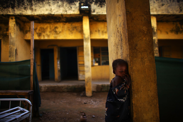 Aishsa Yusufa stands against a pillar outside the Doctors Without Borders ward in Anka, Nigeria. The 4-year-old girl is enrolled in a program at the clinic to treat her for high levels of lead.