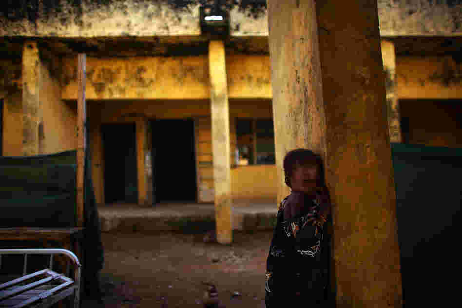 Aishsa Yusufa stands against a pillar outside the Doctors Without Borders ward in Anka, Nigeria. The 4-year-old girl is enrolled in a program at the clinic to treat her for high levels of lead.
